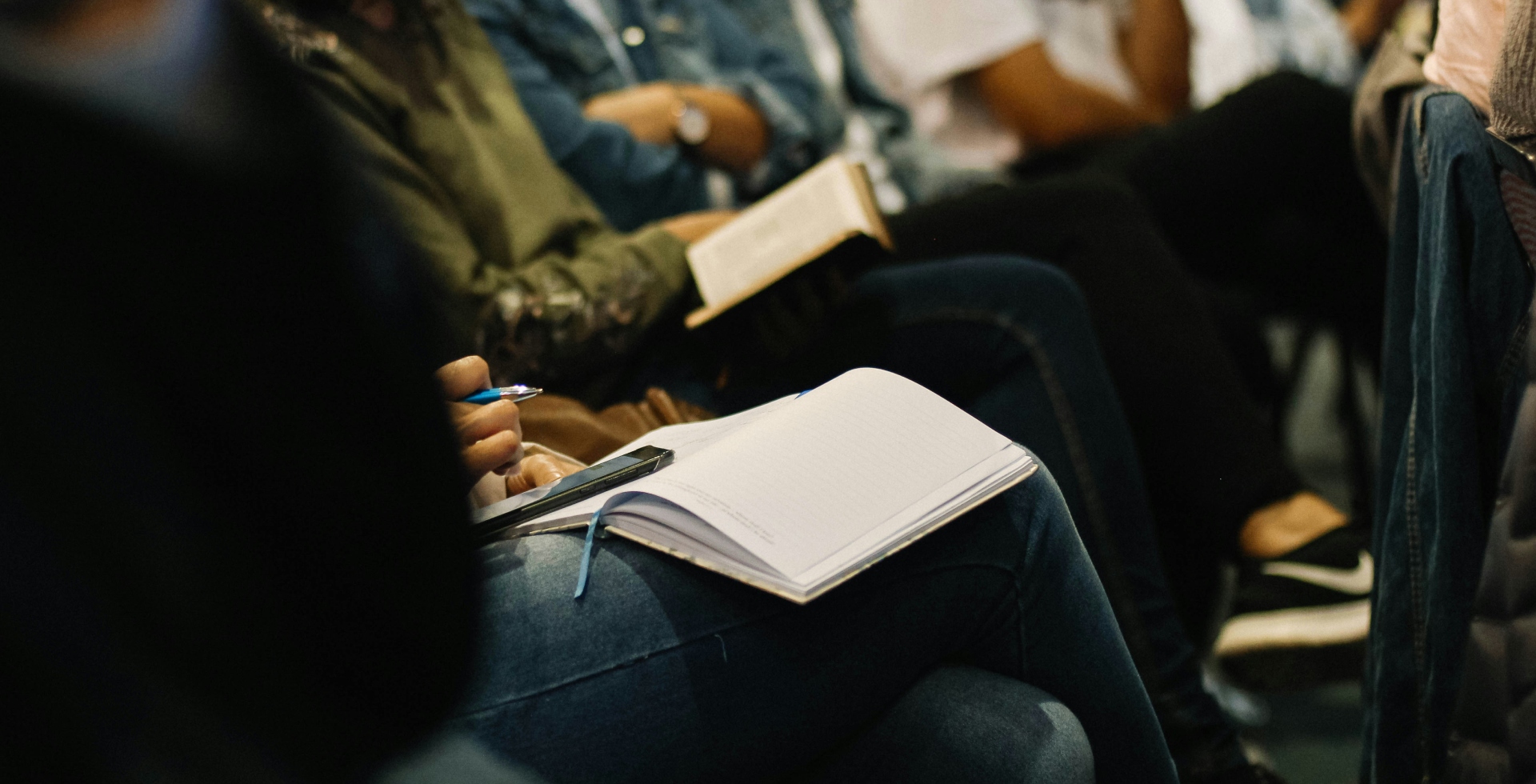 Close-up of people taking notes during meeting.